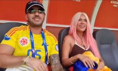 a man and woman sitting next to each other at a soccer game wearing yellow shirts