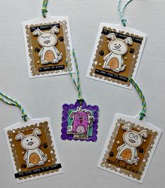 four small tags with animals on them hanging from twine string and some colored paper