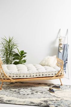 a bed that is sitting in the middle of a room next to a potted plant