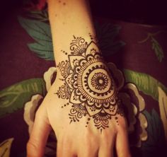 a woman's hand with a henna tattoo on it