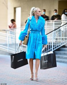 a woman in a blue coat carrying shopping bags