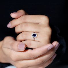 a woman's hand holding a ring with a blue stone in the middle and a white diamond on top