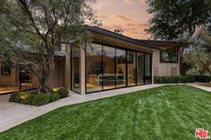 a house with glass walls and trees in the yard