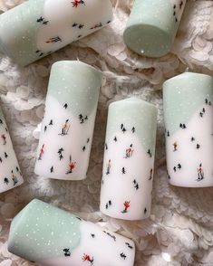 several white candles with designs on them sitting on a lace covered tablecloth, next to each other