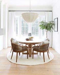 a dining room table with four chairs and a potted plant in the corner on top