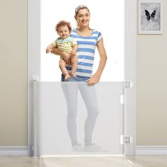 a woman holding a baby standing in front of a door with a photo on it