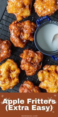 apple fritters are on a cooling rack next to a cup of milk and an orange