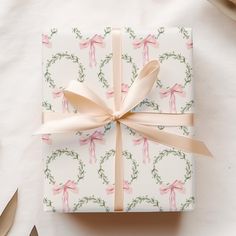 a present wrapped in white wrapping paper with pink bows and ribbons on top of it