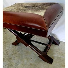 a brown leather ottoman sitting on top of a cement floor