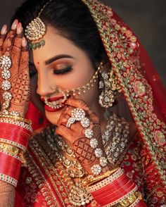 a woman in red and gold bridals with her hands to her face, looking down