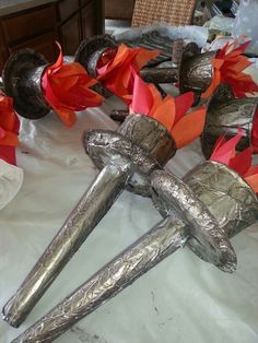 some silver objects are on a table with red flowers