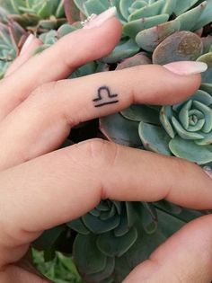 a person with a small tattoo on their finger next to a succulent plant