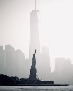 the statue of liberty is surrounded by tall buildings in new york city on a foggy day