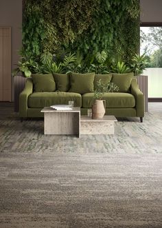 a living room with a couch, coffee table and green plants on the wall behind it