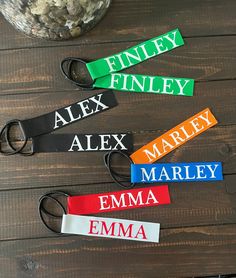 four personalized name tags are shown on a wooden table next to a glass vase