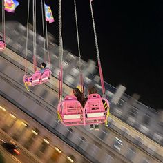 two girls ride on pink bumper cars in the air at an amusement park or carnival