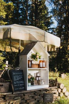 a small white house with an awning on it's roof and shelves filled with items