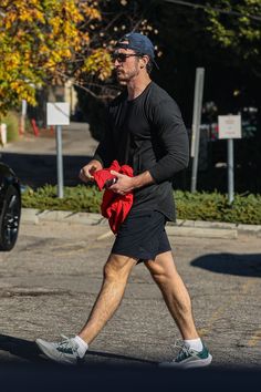 a man in black shirt and shorts walking on street