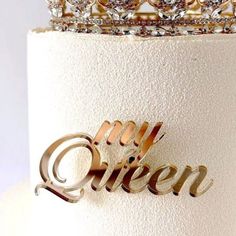 a white cake topped with a gold crown and the word queen on it's side