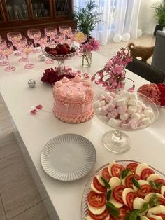 a table topped with cakes and desserts on top of a white table covered in pink flowers