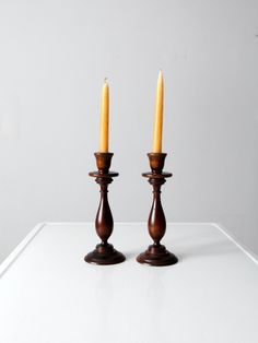 two wooden candlesticks sitting on top of a white table