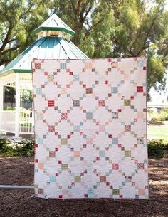 a quilt hanging from a tree in front of a gazebo