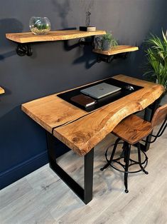 a wooden table with two shelves on the wall above it and a laptop computer sitting on top of it