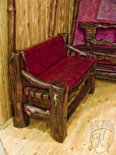 a red couch sitting next to a wooden chair on top of a hard wood floor