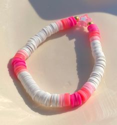 a pink and white beaded bracelet sitting on top of a table