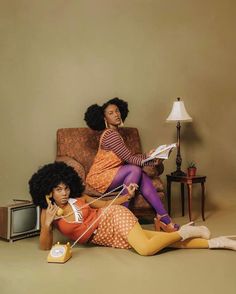 two women sitting on a couch in front of a tv and an old fashioned telephone