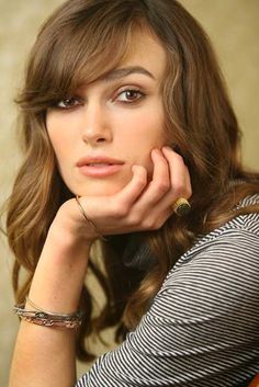 a woman with her hand on her chin and looking at the camera while sitting down