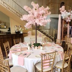 a table set up with pink flowers and balloons for a baby shower or birthday party