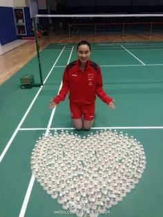 a woman standing on top of a tennis court with lots of cups in the shape of a heart