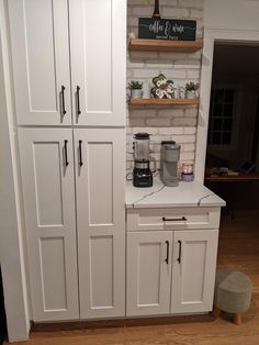 a kitchen with white cupboards and shelves filled with coffee pots on top of them