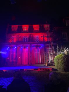 the stage is lit up with red and blue lights in front of an old building