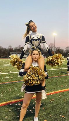 two cheerleaders standing on the sidelines with their poms