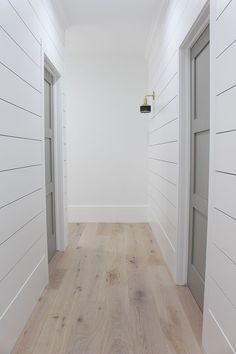 an empty room with white walls and wood floors is seen in this image from the hallway