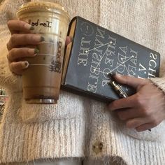 a person holding a book and a cup