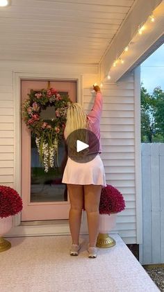 a woman standing on top of a porch next to flowers