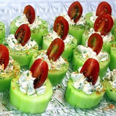 several pieces of green apple with tomatoes and whipped cream on them, sitting on a glass platter