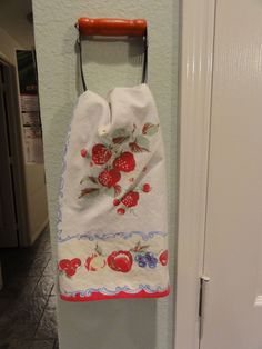 a kitchen towel hanging on the wall next to an open door with a red handle