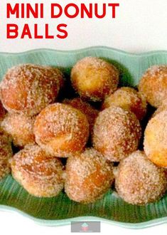 a green bowl filled with sugar covered doughnuts on top of a white table