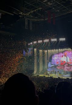 the stage is lit up with confetti as people watch from the stands in front of it