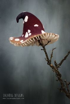 a mushroom with white spots on it sitting on top of a tree branch in front of a gray background