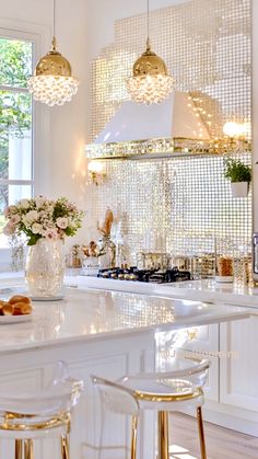 a white kitchen with gold accents and hanging lights