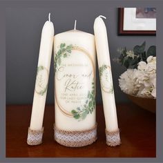 three candles are sitting next to each other on a table with flowers in the background