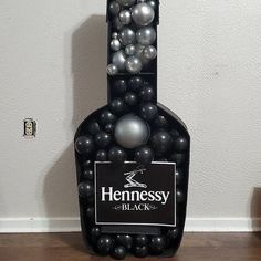 a bottle filled with black and silver balls sitting on top of a wooden floor next to a wall