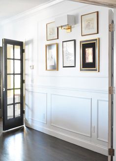 an empty room with framed pictures on the wall and a black door in front of it