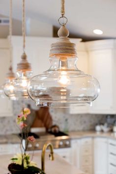 an image of a kitchen setting with lights hanging from the ceiling and flowers on the counter