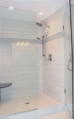 a walk in shower sitting next to a white tiled wall and floor with glass doors